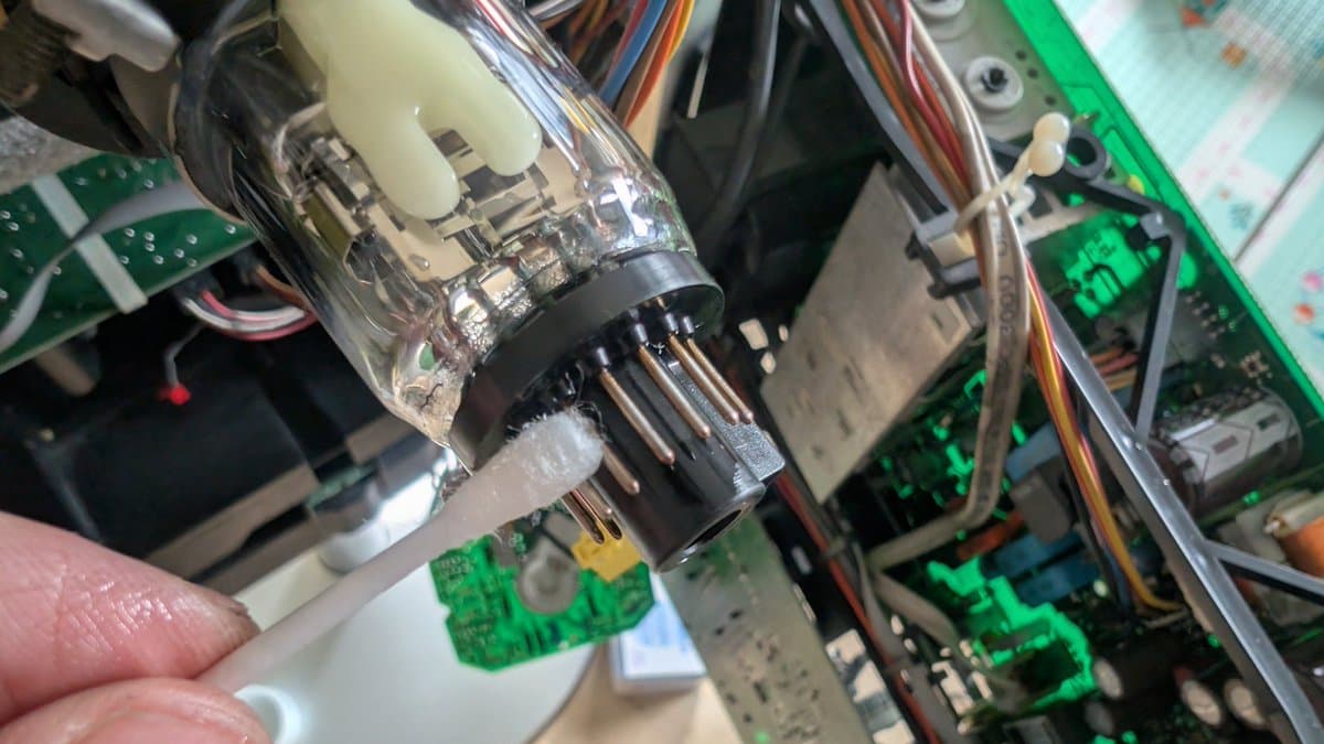 Applying DeoxIT to oxidized CRT connector pins on a Bang & Olufsen Beovision 1, with green circuit boards visible in background.